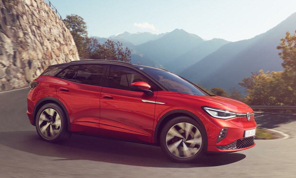 En röd Volkswagen e-Tron kör nedför en bergsväg. (AI text)