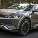 En silver Hyundai EV kör nerför en väg. (AI text)