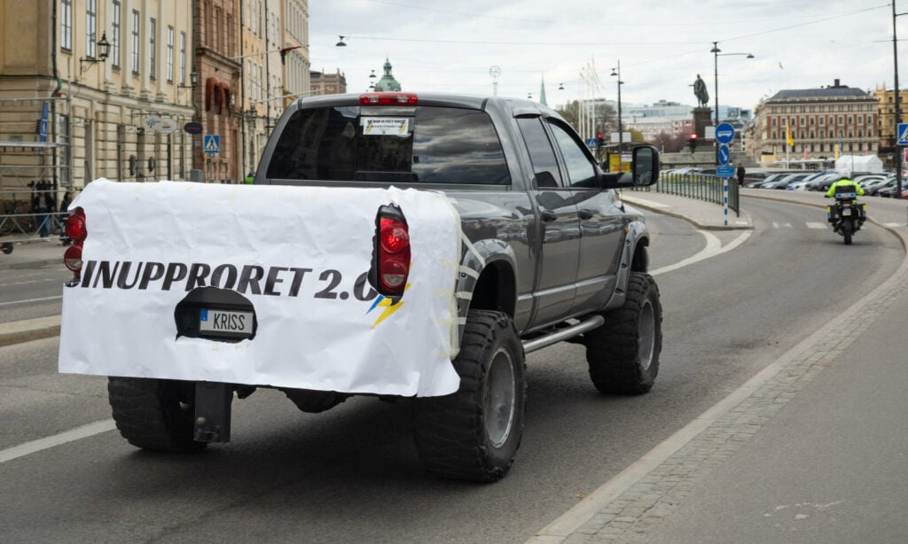 En lastbil med en banner drivs nerför en stadsgata. (AI text)
