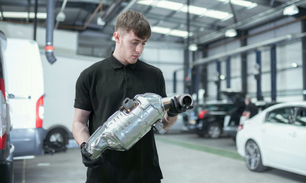 En man inspekterar en bil i en garage. (AI text)