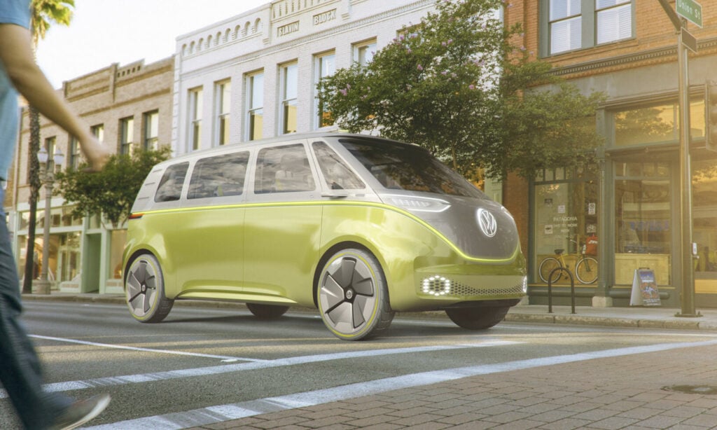 En man promenerar förbi en grönt Volkswagen-buss på en stadsgata. (AI text)