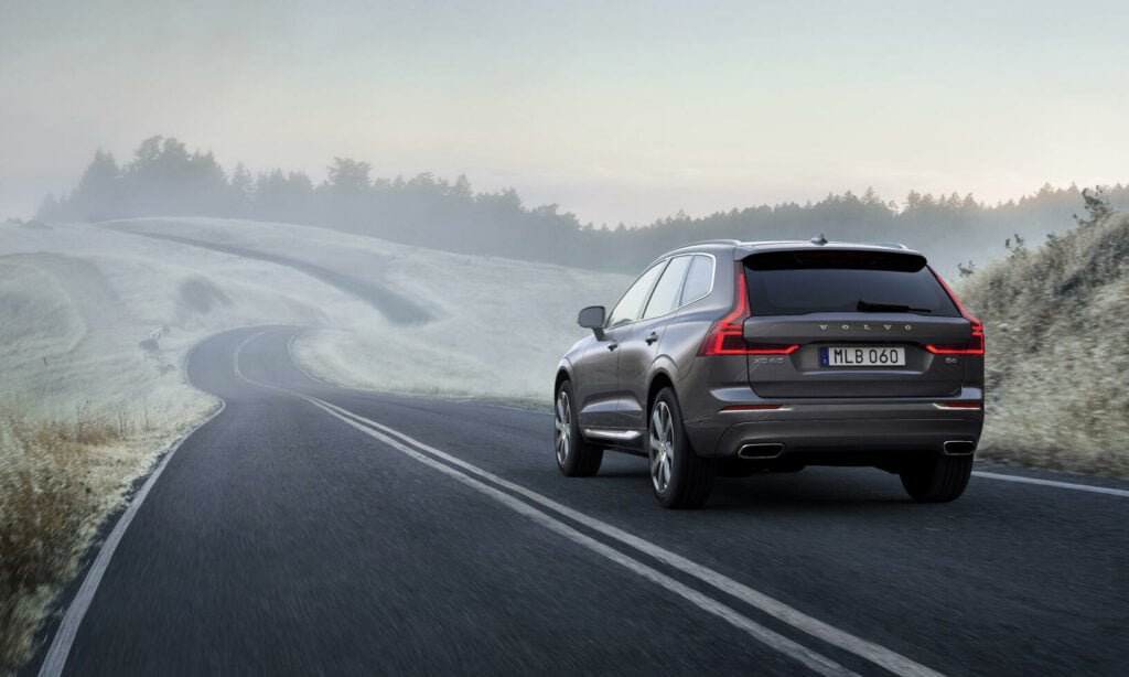 En Volvo XC90 SUV kör nedför en landsväg. (AI text)