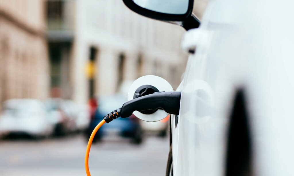 En vit bil är uppkopplad till en elbilsladdare. (AI text)