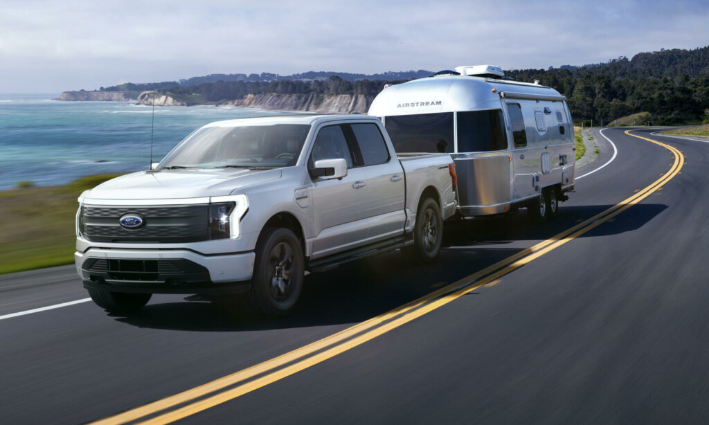 En 2020 års Ford F-150 lastbil och släp på en väg med en campingvagn monterad på sidan. (AI text)