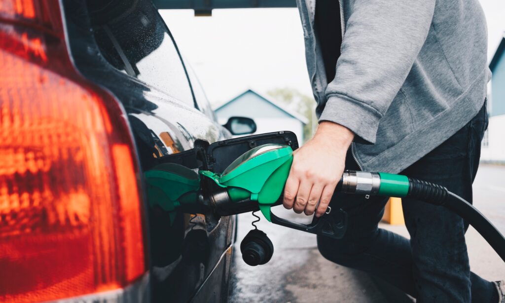 En man tankar sin bil med bränsle på en bensinstation. (AI text)
