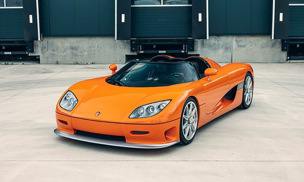 En Koenigsegg K1 supersportbil parkerad framför ett byggnad. (AI text)