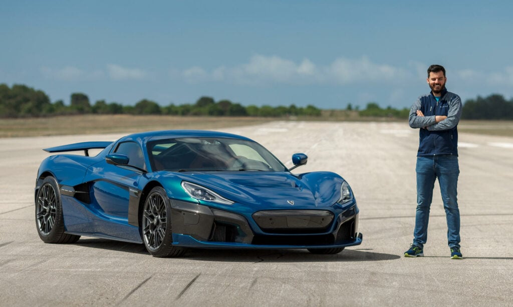 En man står bredvid en blå sportbil. (AI text)