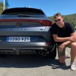 En man poserar med sin bil framför ett berg. (AI text)