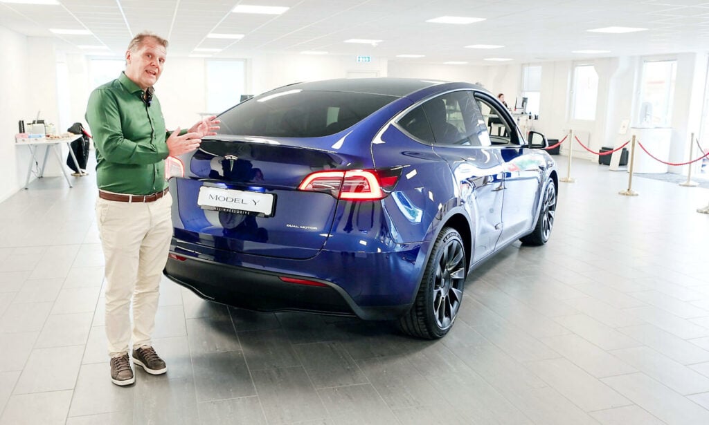 En man står bredvid en Tesla Model S i en showroom. (AI text)