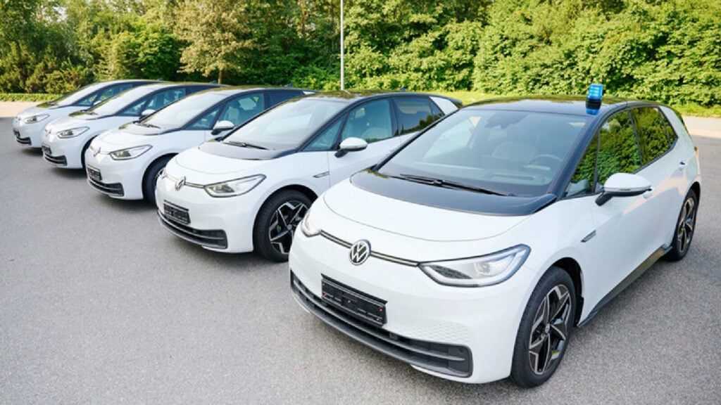 En grupp vita Volkswagen e-Golf-bilar parkerade i en parkeringsplats. (AI text)