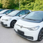En grupp vita Volkswagen e-Golf-bilar parkerade i en parkeringsplats. (AI text)