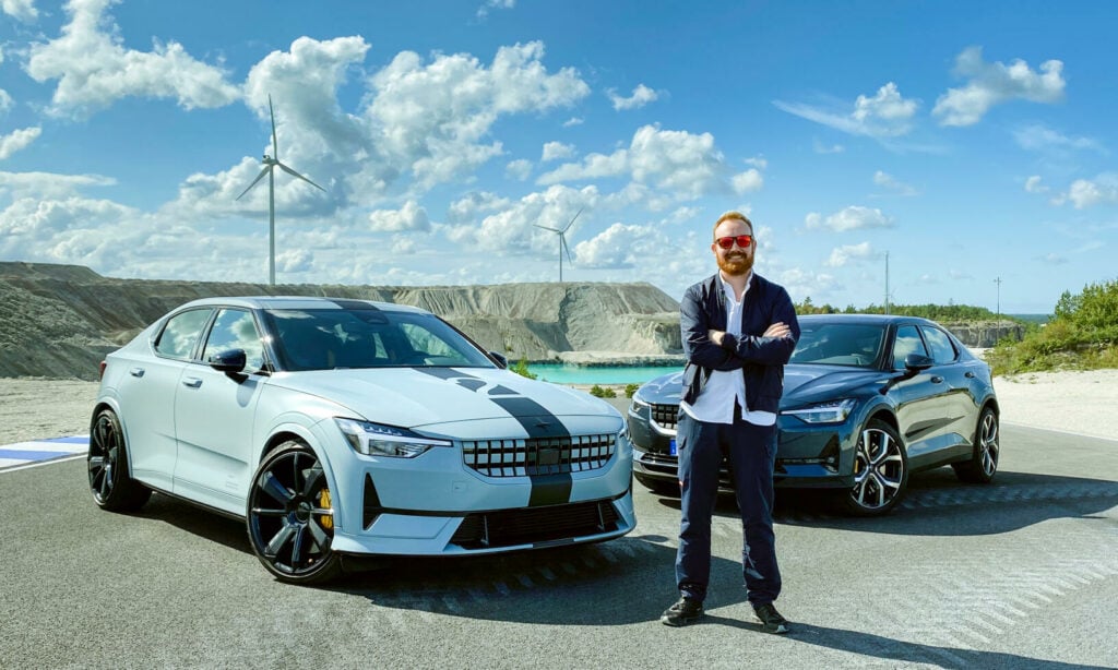 En man står bredvid en bil och vindkraftverk. (AI text)