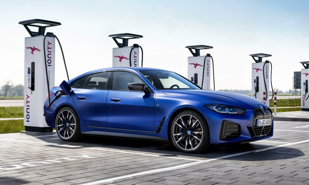 BMW i3 E30, en elätelektrisk bil, laddar på en laddstation. (AI text)