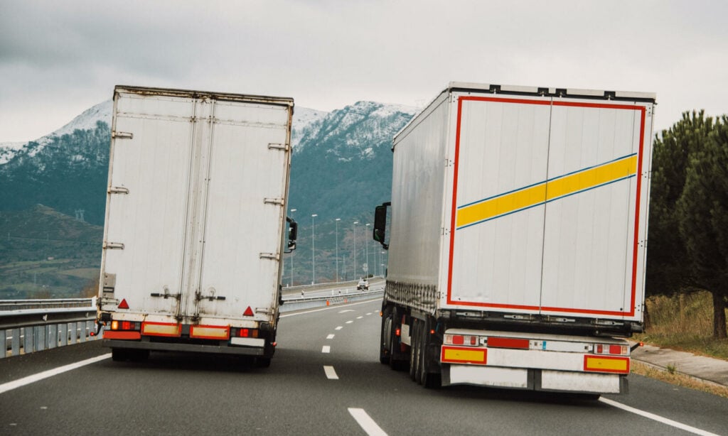 Två lastbilar kör på motorvägen. (AI text)