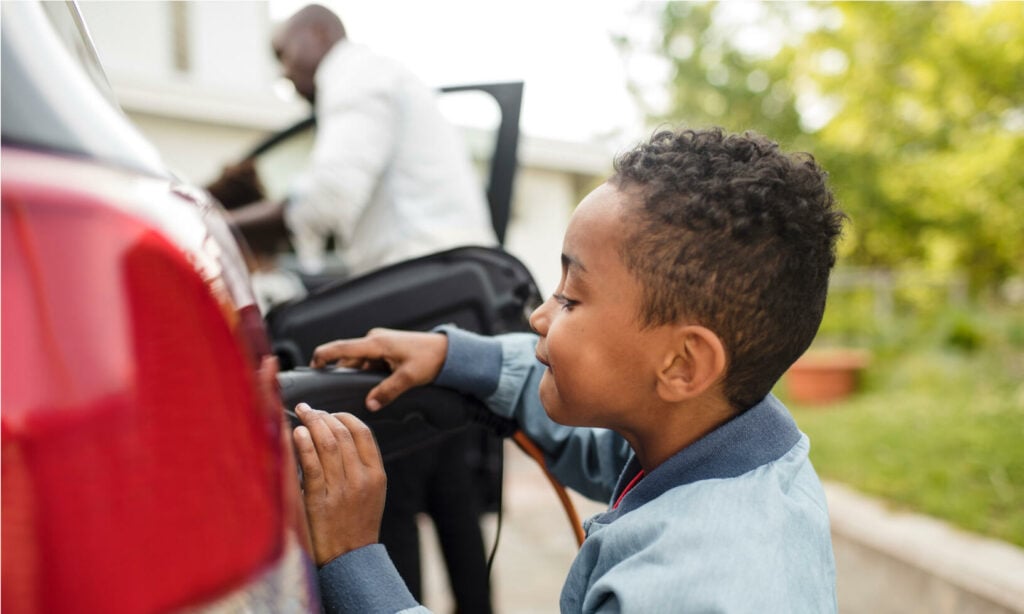 En ung pojke monterar en bilbatteri i sin bil. (AI text)