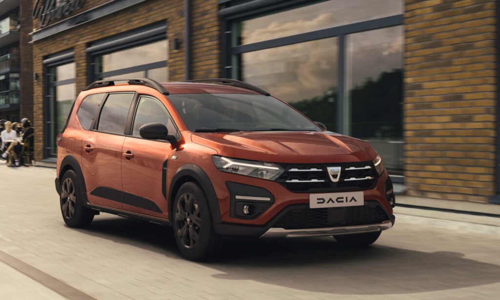 En röd Dacia DX kör ner en stadsgata. (AI text)