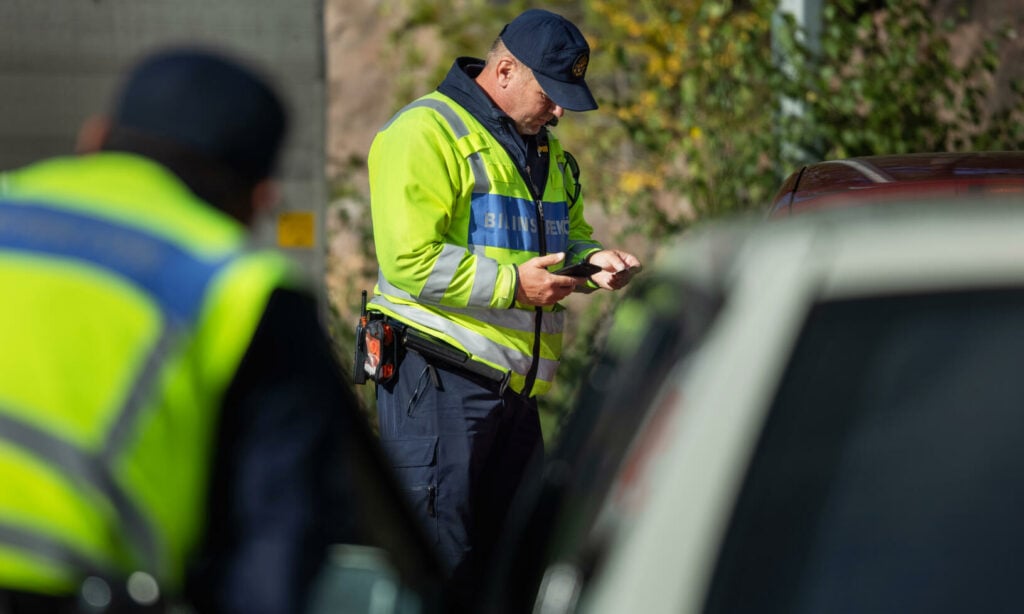 En polis kontrollerar fordonsstatus på en bil. (AI text)