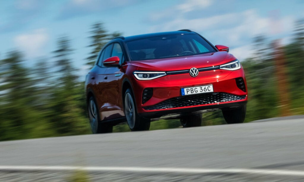 En röd Volkswagen e-Tron kör nerför en bergsväg. (AI text)