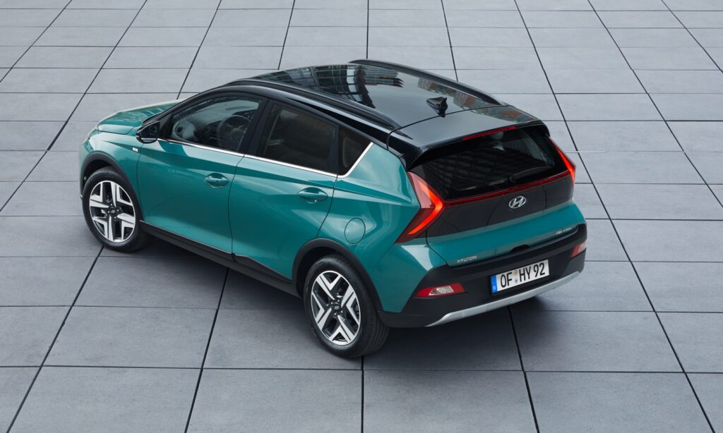 En grön Hyundai Ioniq parkerad på en klinkergolv. (AI text)