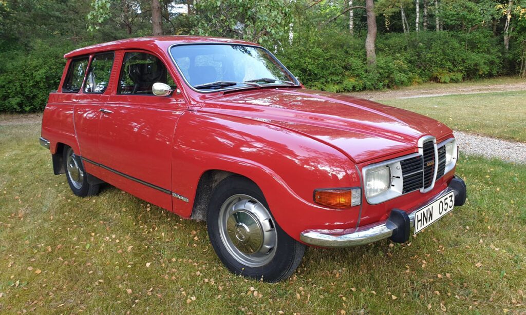 En röd bil parkerad på en gräslig äng. (AI text)