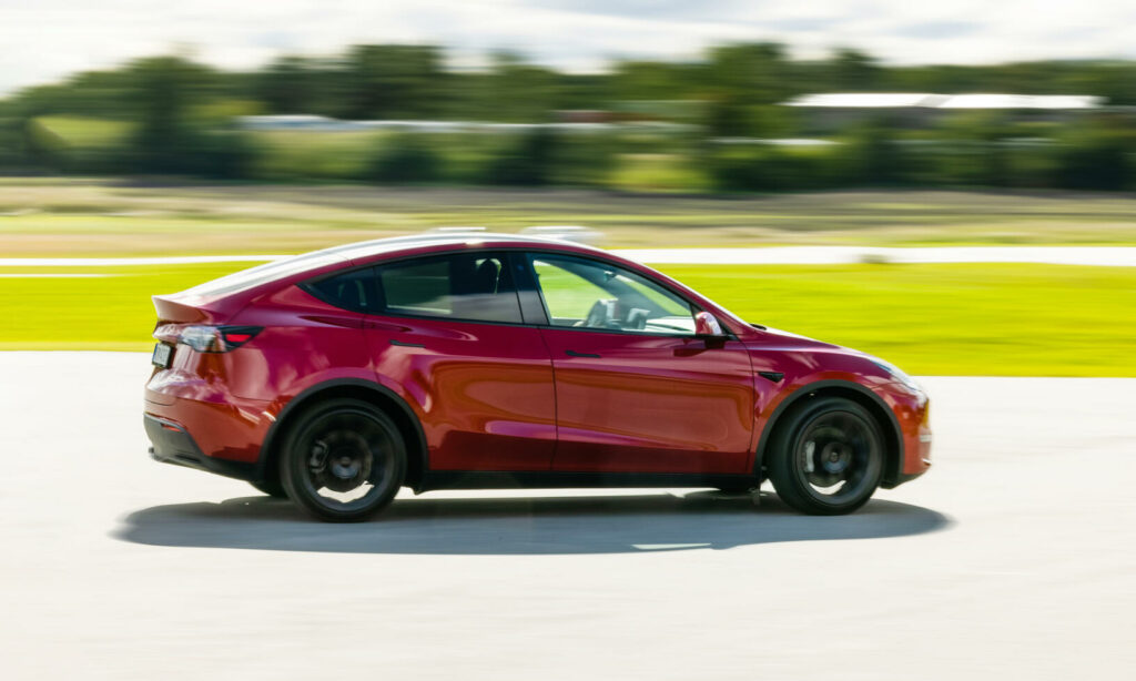 En röd Tesla Model Y kör på ett racebana. (AI text)
