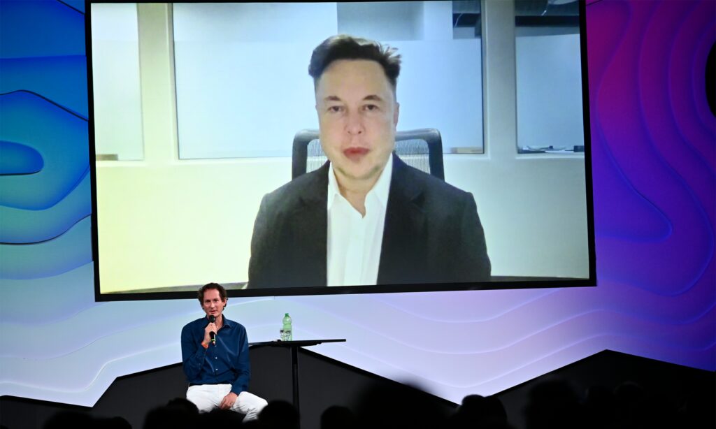 Elon Musk deltog i Italian Tech Week 2021 i Turin via videolänk. På scen Stellantis och Ferraris styrelseordförande John Elkann.