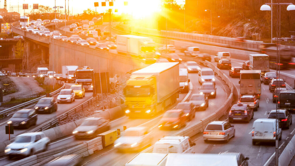 En stadsgata med biltrafik på gång på solnedgången. (AI text)