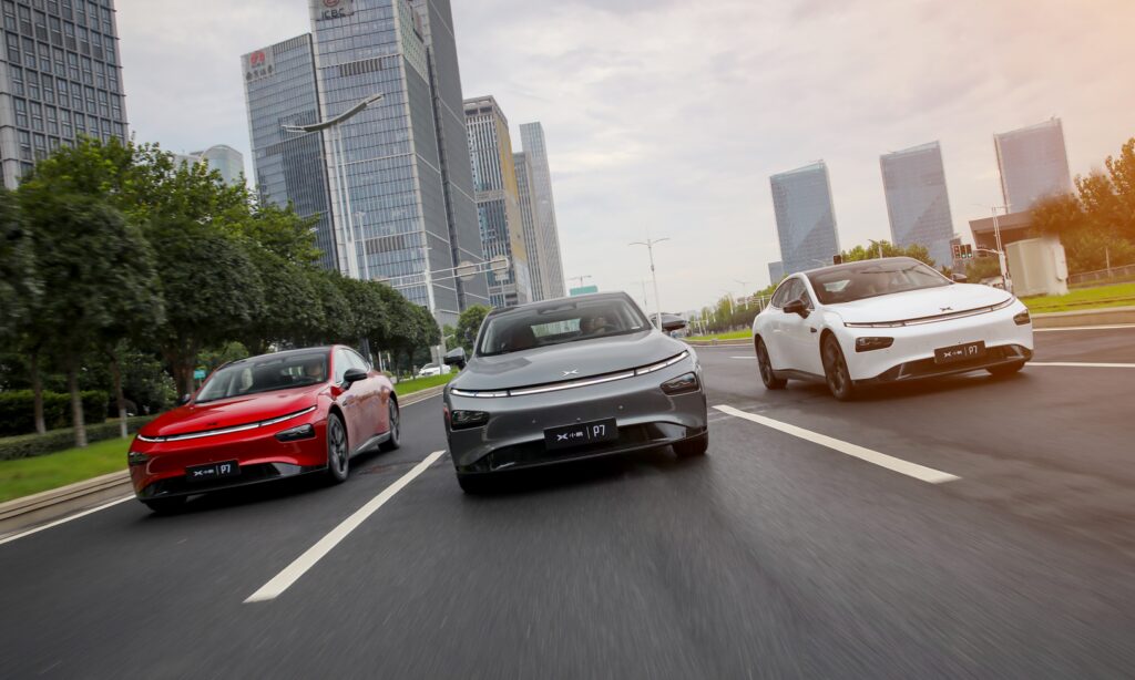 Tre elbilar kör nedför en stadsgata. (AI text)