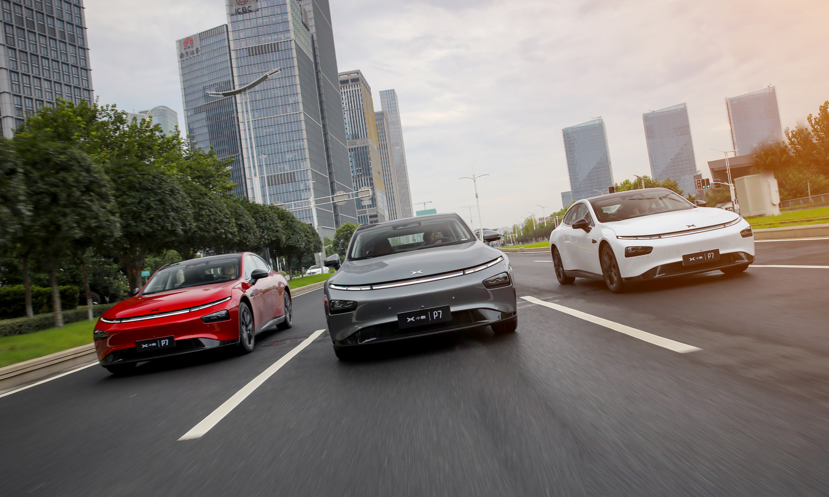 Tre elbilar kör nedför en stadsgata. (AI text)