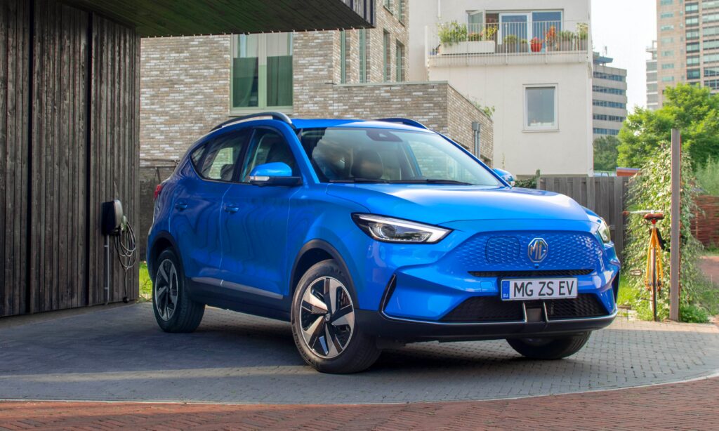 En blå Nissan EQ parkerad framför en husfasad. (AI text)