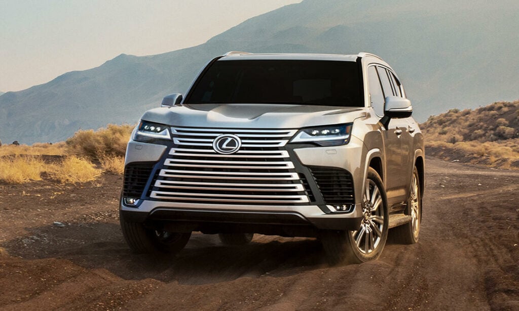 En silverfärgad Lexus SUV kör nedför en grusväg. (AI text)