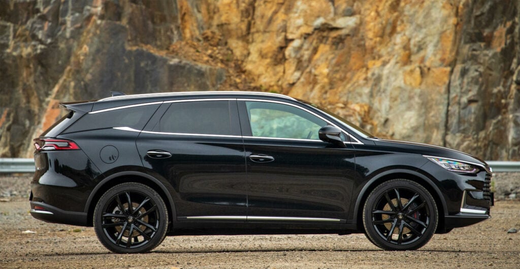 En svart SUV parkerad framför en bergig bergskedja. (AI text)