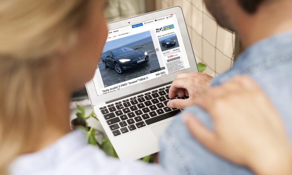 En man och kvinna tittar på en bil på en dator. (AI text)