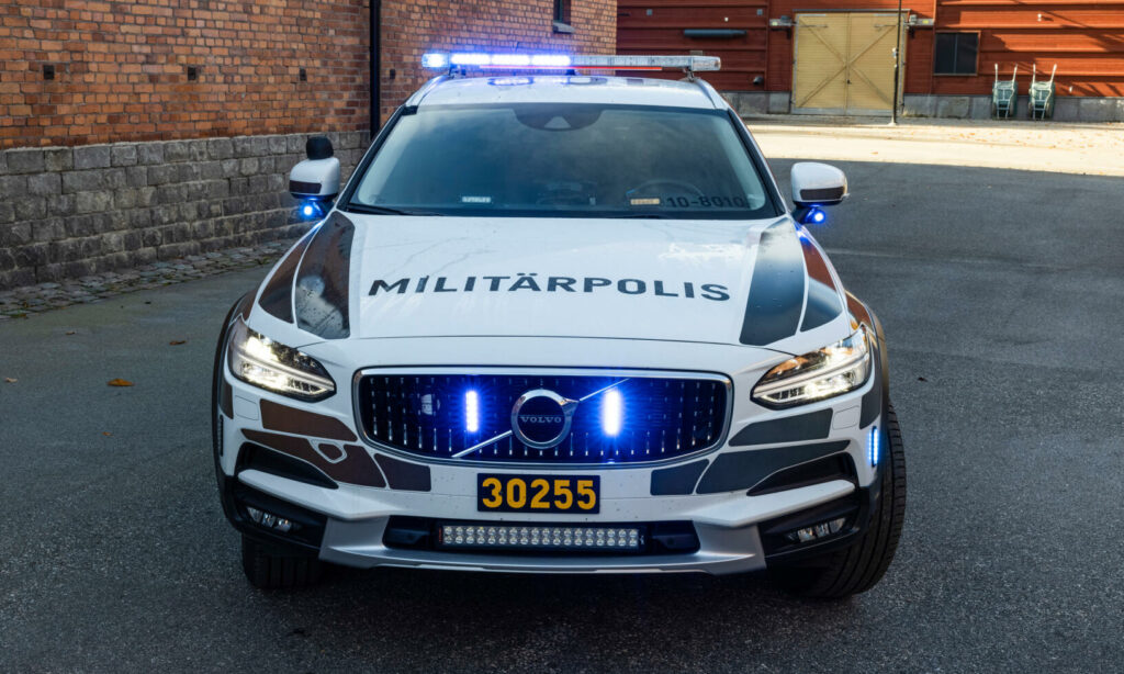 En polisbil parkerad framför ett tegelbyggnad. (AI text)