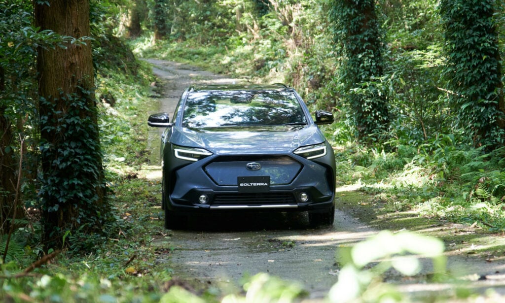 En svart SUV körer nedför en grusväg i skogen. (AI text)