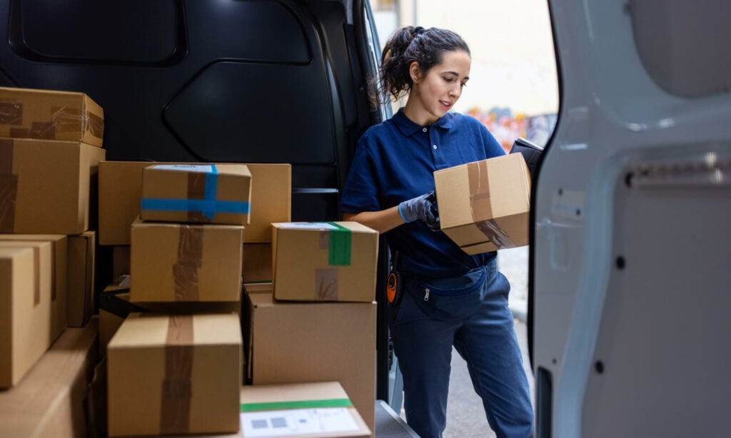 En kvinna lastar lådor i en bil. (AI text)