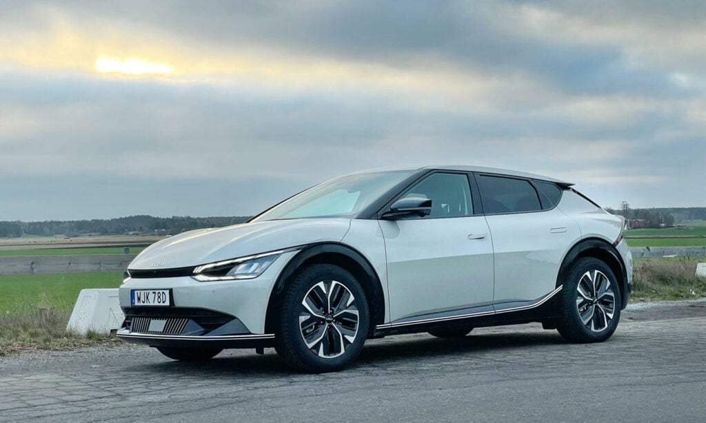 En vit Nissan e EV parkerad vid en grusväg. (AI text)