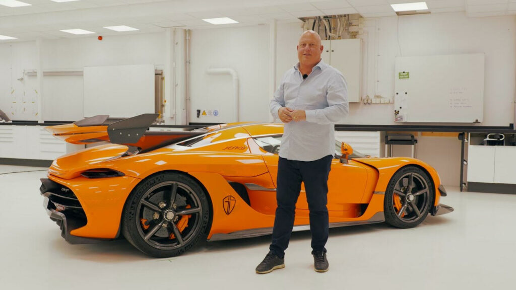 En man står framför en orange sportbil. (AI text)