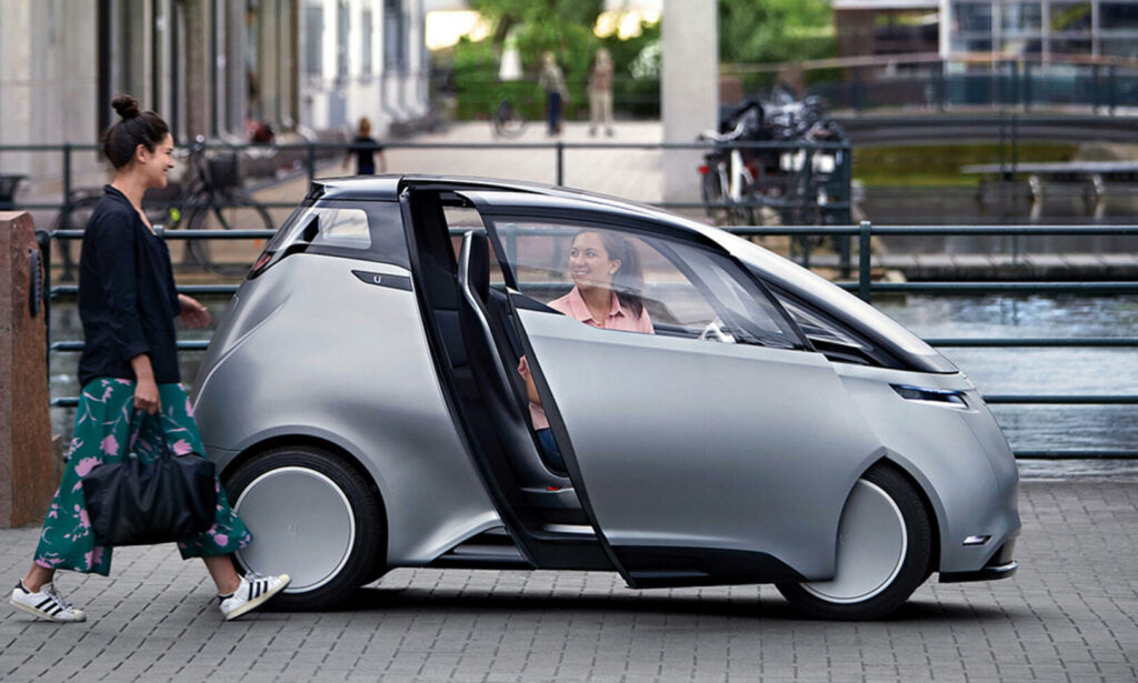 En kvinna står bredvid en futuristisk bil. (AI text)