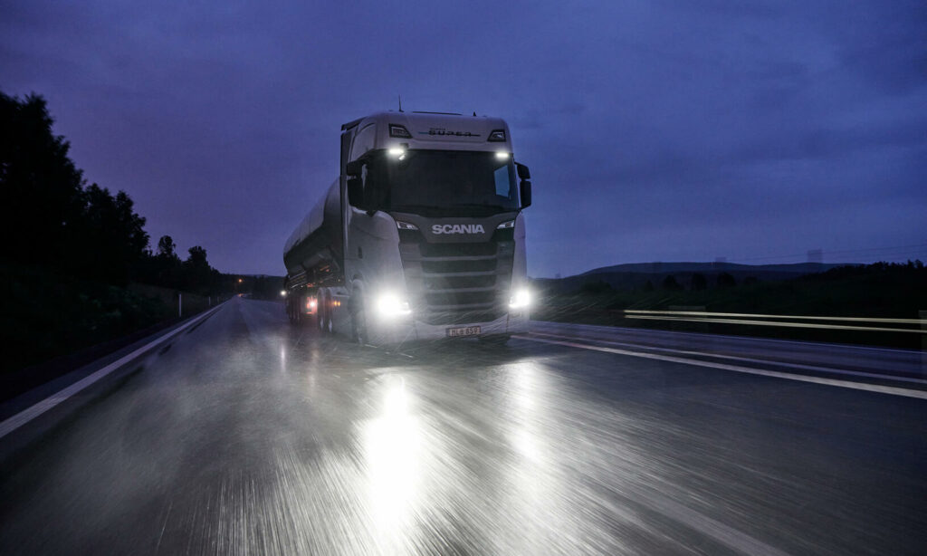 En lastbil kör på en väg på natten. (AI text)