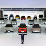 En man står framför en stor display med elbilar. (AI text)