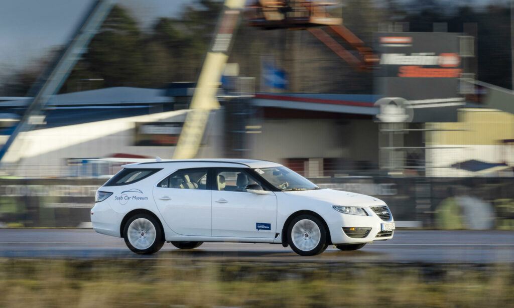 En vit bil kör på en bana. (AI text)