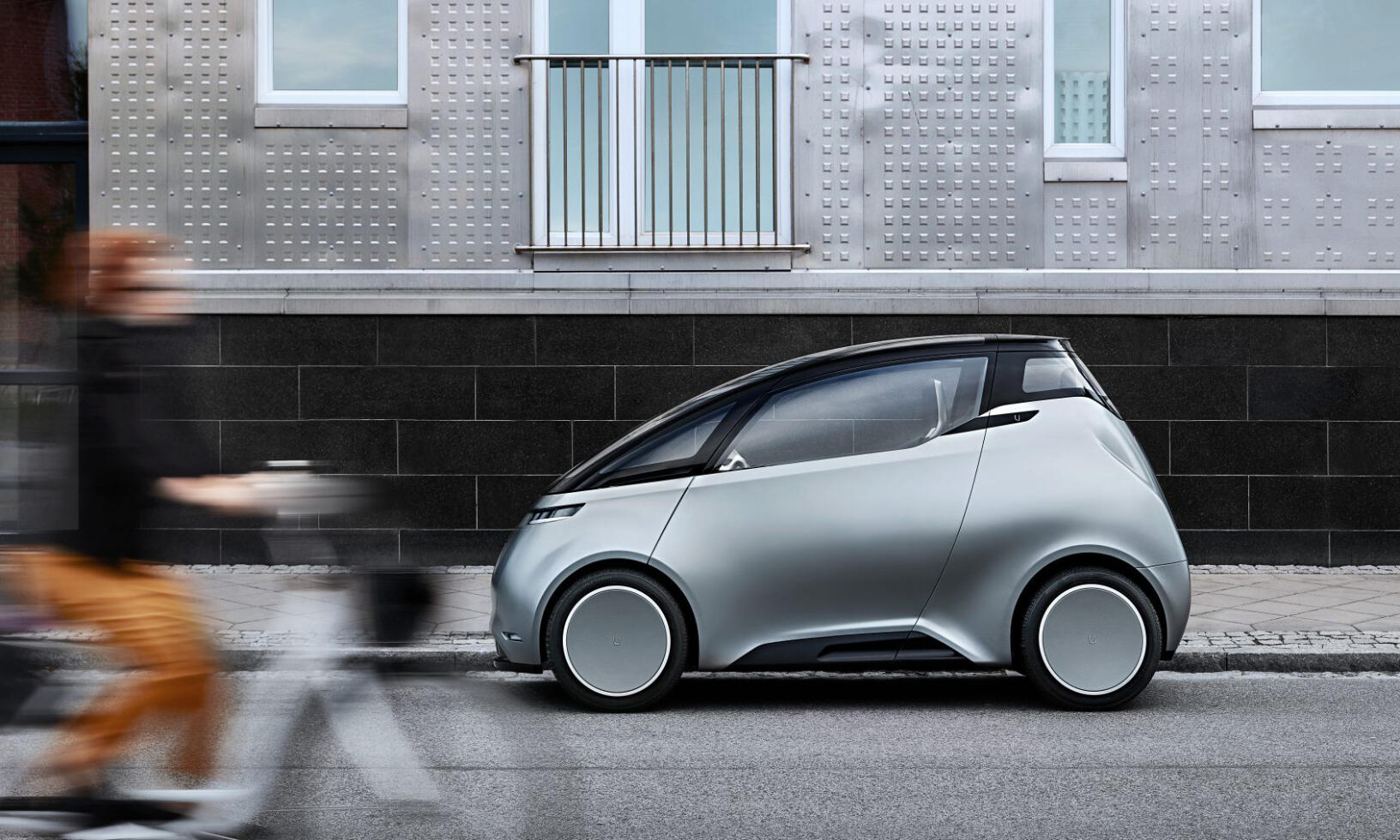 En kvinna cyklar bredvid en futuristisk bil. (AI text)