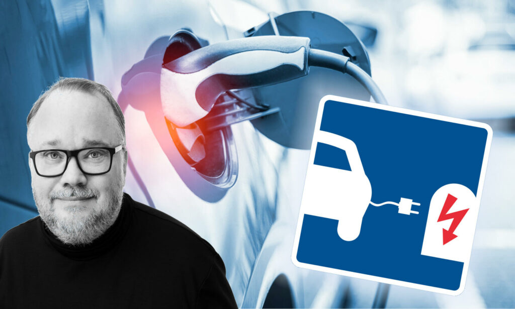 En man står bredvid en bil som laddas vid en elbilsladdstation. (AI text)