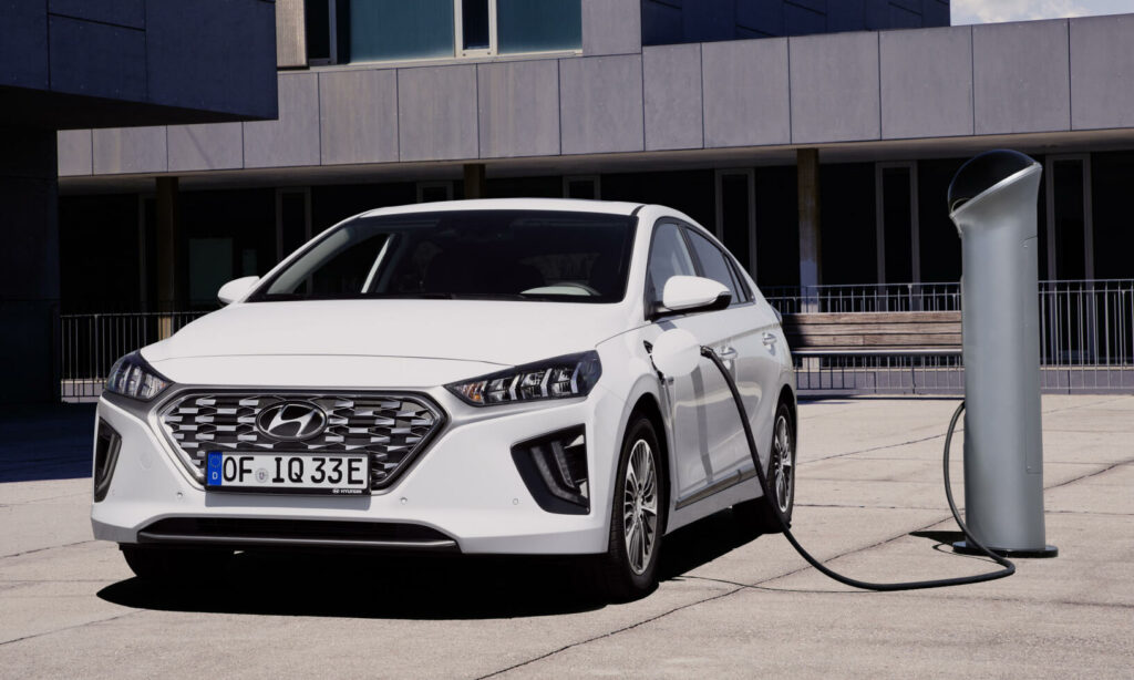 En vit Hyundai Ioniq elbil laddar vid en laddstation. (AI text)