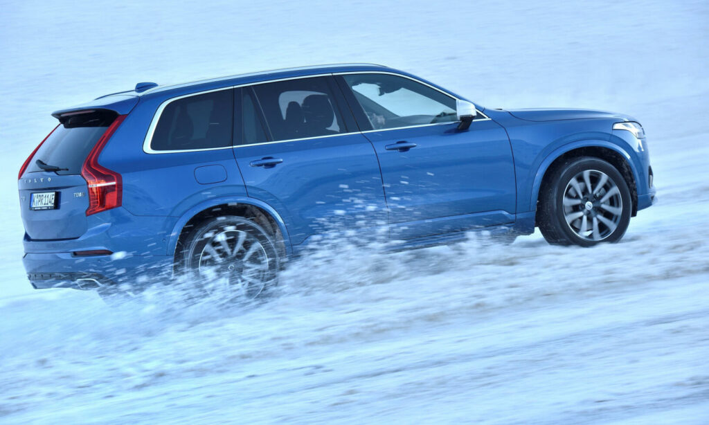 En Volvo XC90 SUV kör på snöiga vägar. (AI text)
