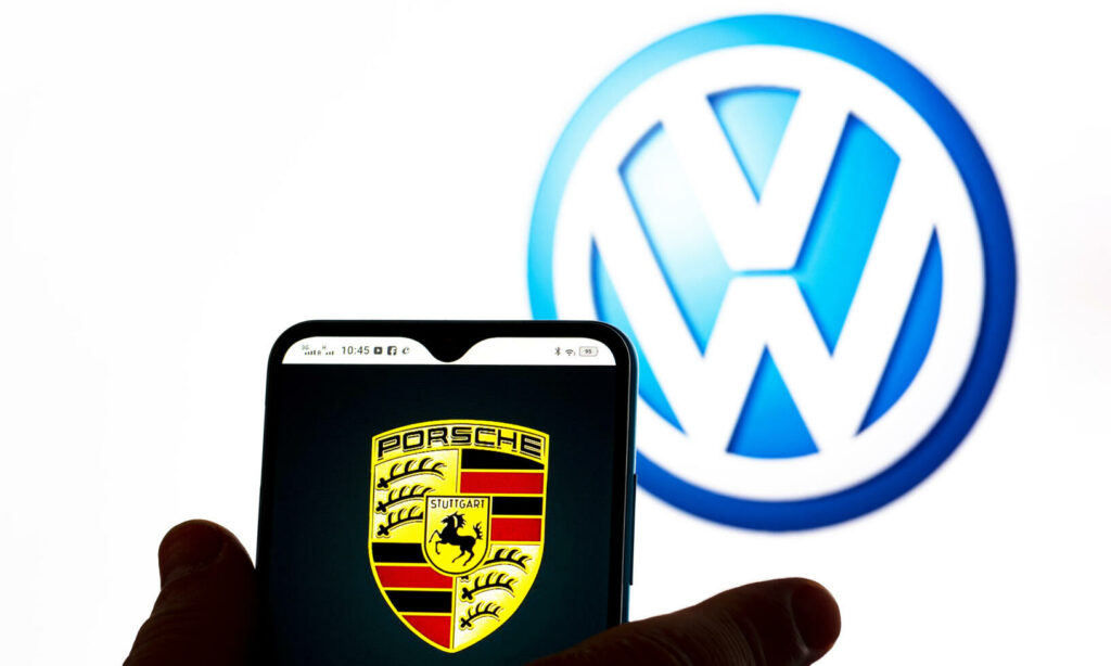 En man håller en smartphone framför Volkswagens logotyp. (AI text)