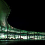 En grön byggnad upplyst på natten. (AI text)