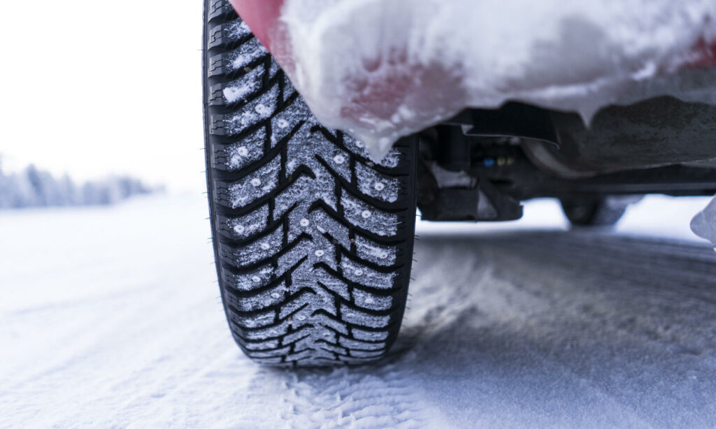 En bil kör på en snöig väg. (AI text)