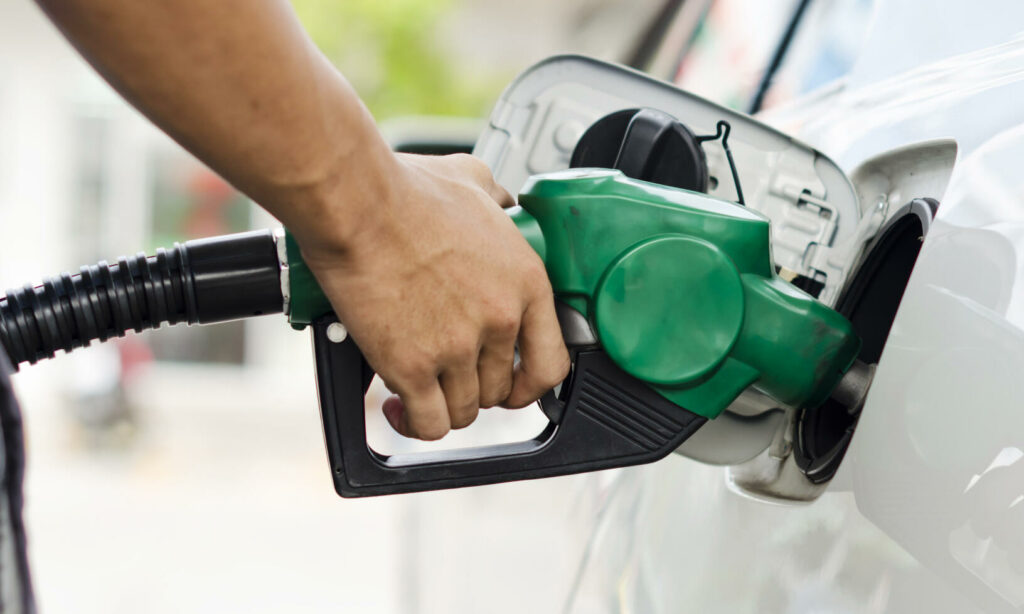 En man tankar sin bil med bränsle på en bensinstation. (AI text)